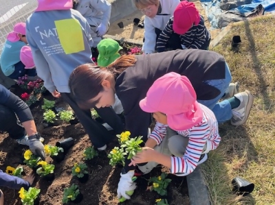 寄せ植え教室において、生産者が園児と一緒に花を植えている様子