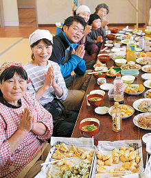コーディネーターを担う田中臣仁朗さん（写真左から3番目）。お昼には、メンバーが持ち寄った野菜などで手づくりする地産地消のおかずやご飯がずらりと並ぶ様子