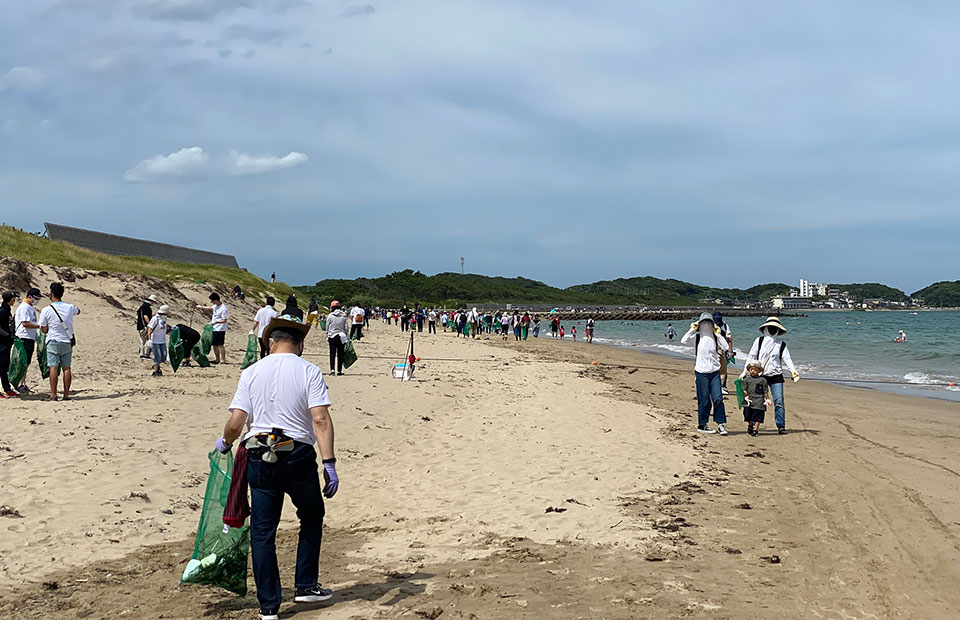 地域の人々が砂浜を清掃している写真