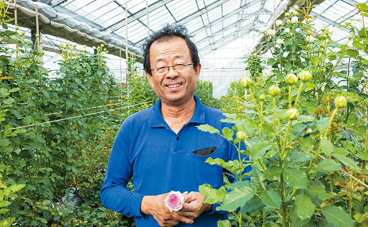 バラ園でバラを持つ花田哲治さんの写真