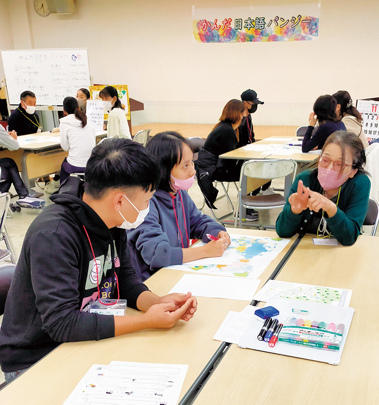 日本語教室でテーブルを真ん中に交流をするたくさんの人たちの写真