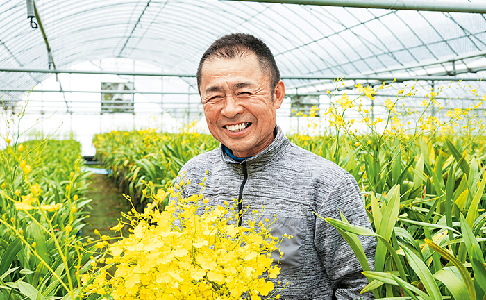 オンシジュームを持って笑顔の高山和博さんの写真