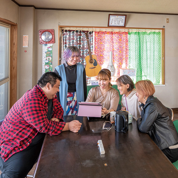 テーブルで談笑する5人の男女の写真 テーブルで談笑する5人の男女の写真