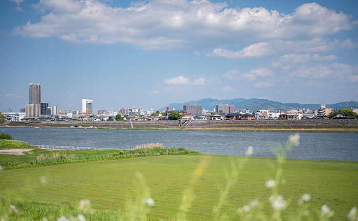 青い空と大きな川に挟まれた久留米の町並みの写真