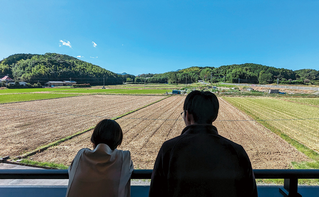 田畑を眺める坂上夫妻の後ろ姿の写真