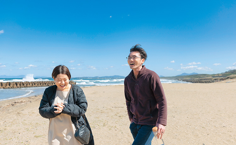 砂浜を歩く坂上夫妻の写真