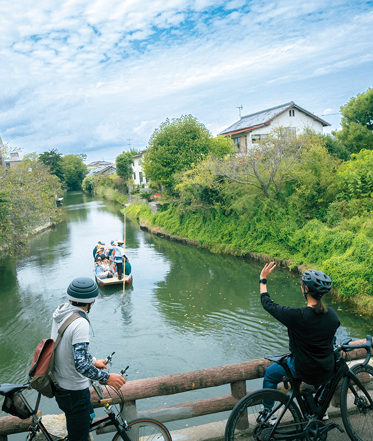 自転車の2人が船に手を振っている写真 自転車の2人が船に手を振っている写真