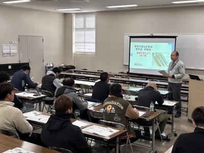 研修を受講しているねぎ若手生産者と会場前方で研修内容を説明する普及指導員